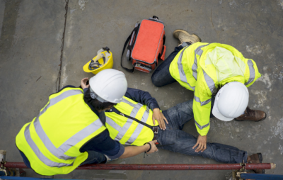 Person on the ground with an injury being helped by two people in hard hats