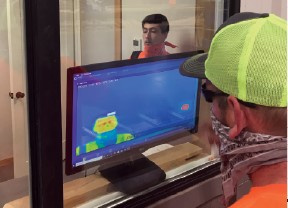 An employee checking another employee's temperature using thermal imaging on a computer