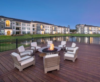 A large residential building in the background with a patio set and fire pit