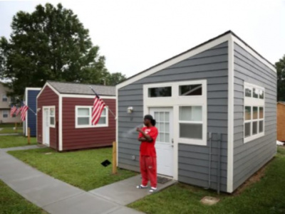 A man standing outside a tiny home along a row of tiny homes