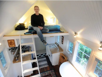 A man sitting on a bunk bed in a tiny home