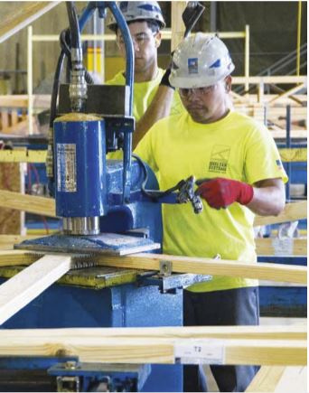 Worker at Shelter Systems pressing a connection plate to a truss