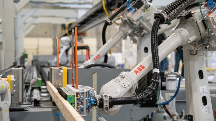 ABB 4600 robots positioning lumber in the press for preplating prior to roof truss assembly. 
